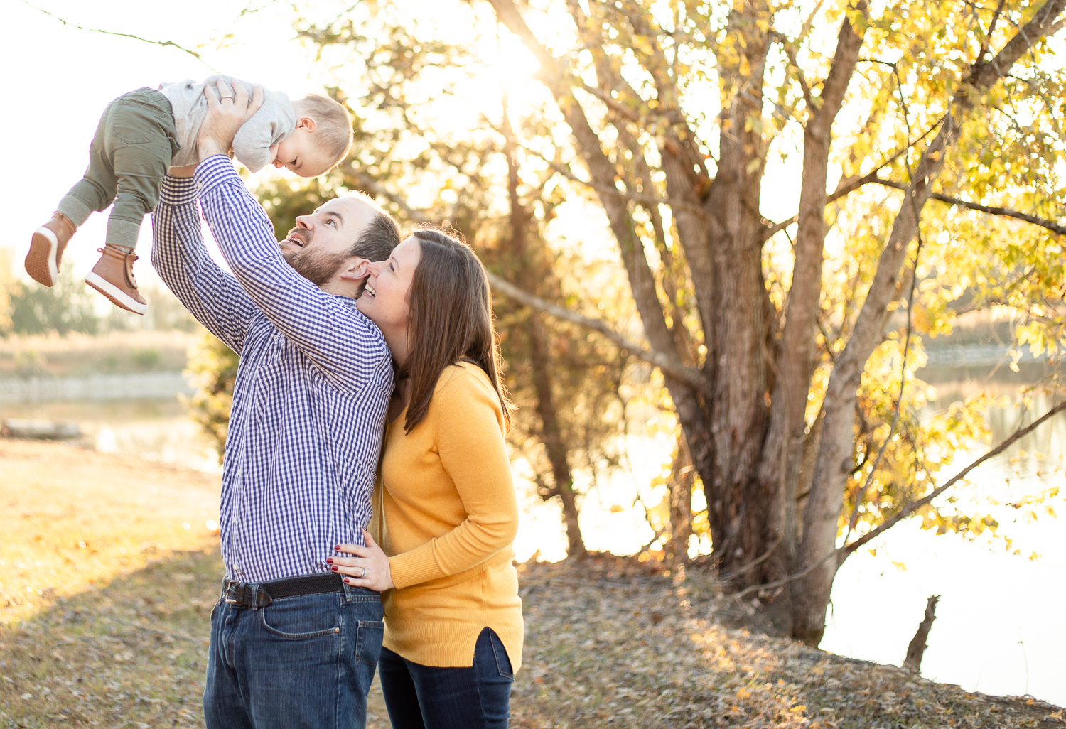 Mom and dad smiling up at sweet baby boy | Jade Alexandria Photography | Fall Family Session Madison County Lake Gurley Alabama